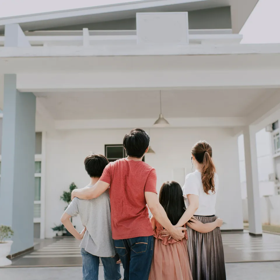 Happy family standing in front of their new home with keys in hand, celebrating homeownership