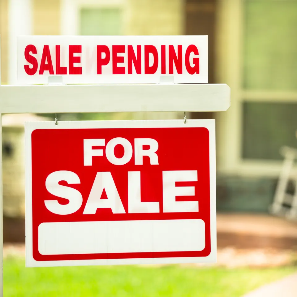 “For Sale” sign in front of a quiet, empty house, symbolizing a home that isn’t selling.