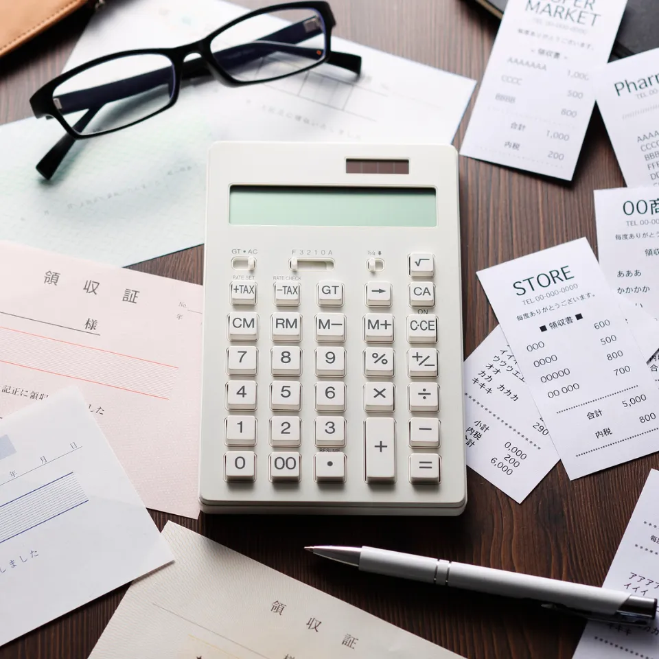 House keys, calculator, and home budget paperwork on a table.