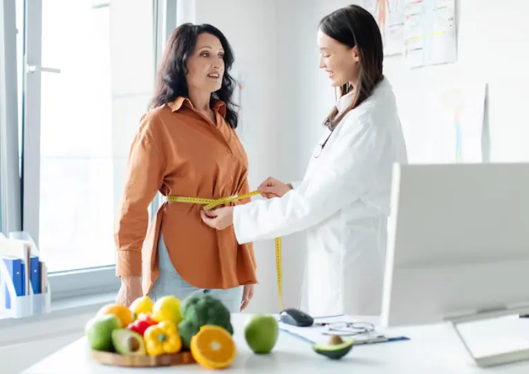 Professional nutritionist measuring waist of mature woman in clinic office