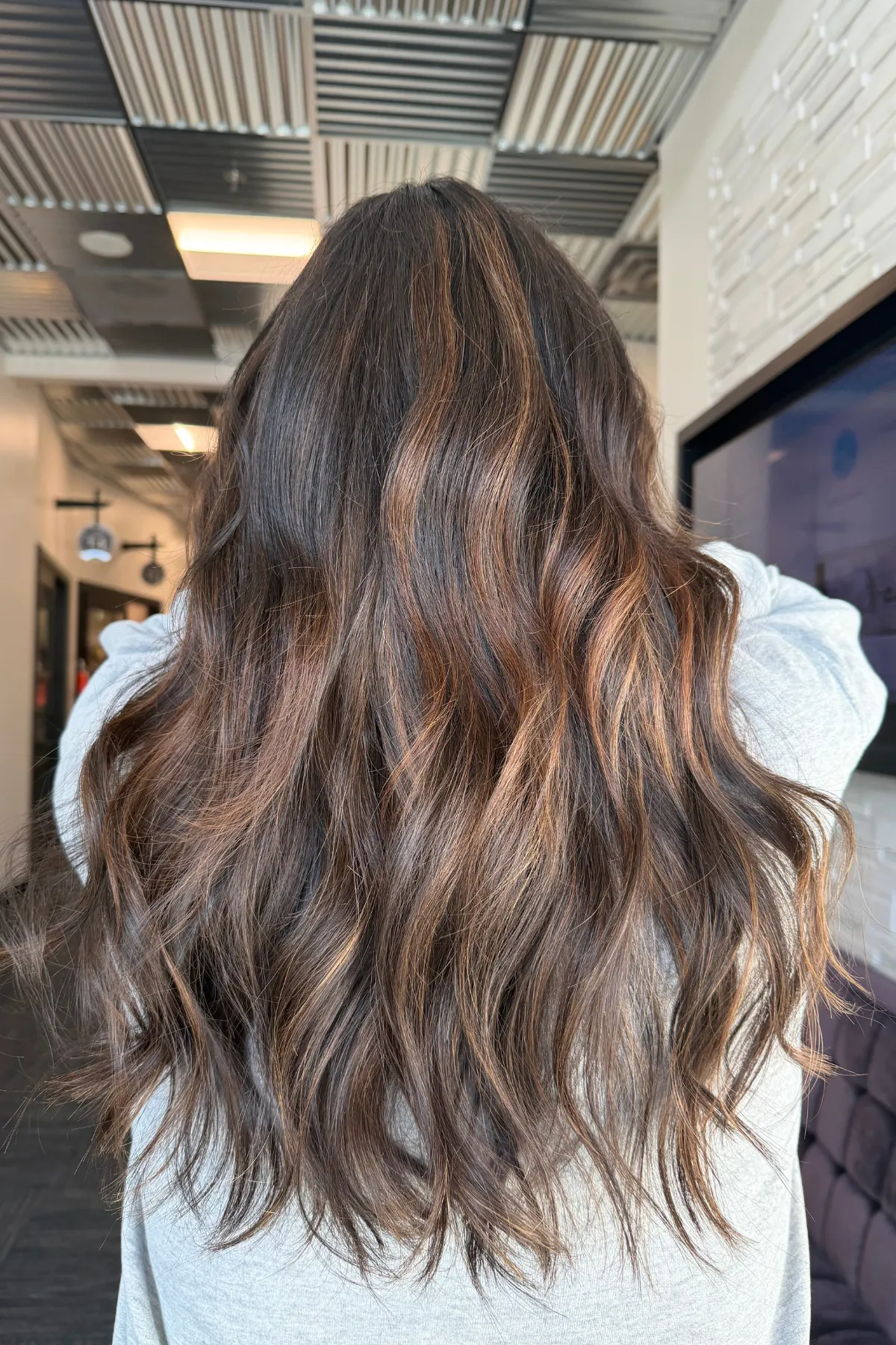 Dimensional brunette hair created with a sew-in topper and tape-in extensions at a Lancaster Pennsylvania hair extension studio