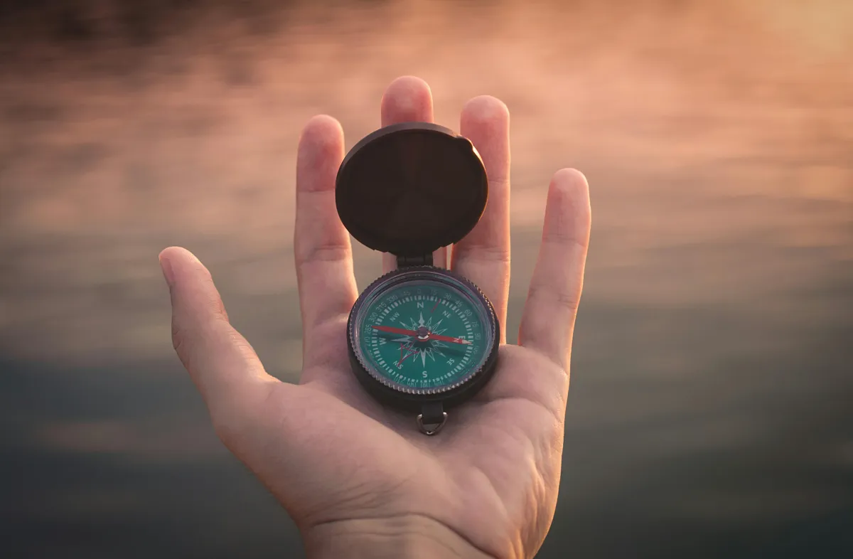 Hand holding a compass.