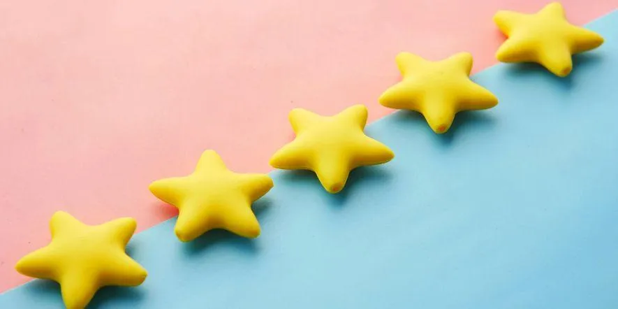 Five yellow stars resting on a pink and blue background as concept for positive review.