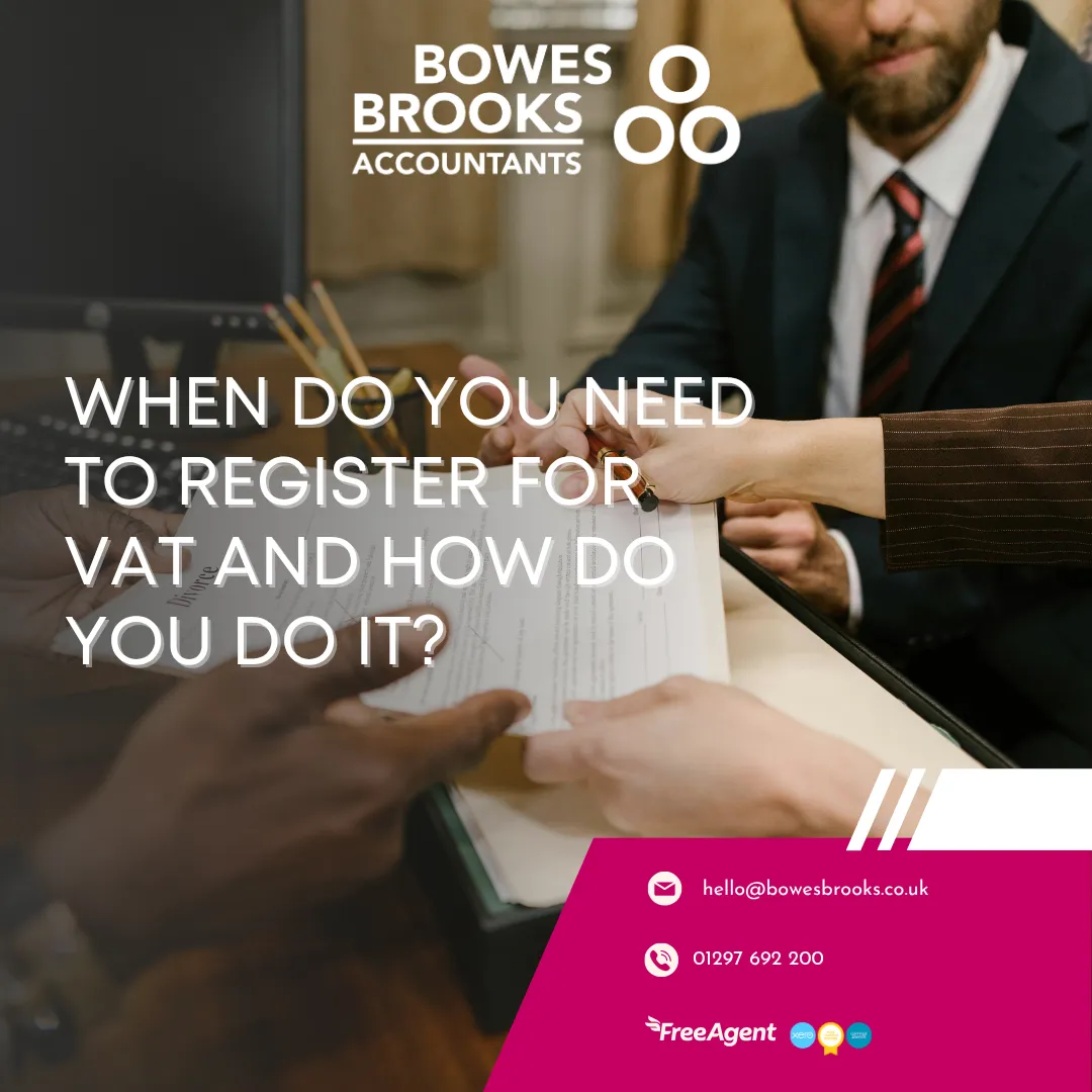 A business owner reviewing financial documents and a VAT registration form on a laptop, with tax paperwork and calculator on the desk.