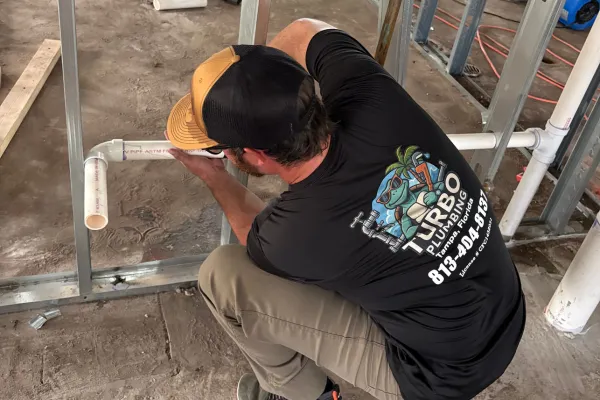 Turbo Plumbing Plumber in Tampa fixing something wearing a turbo plumbing shirt