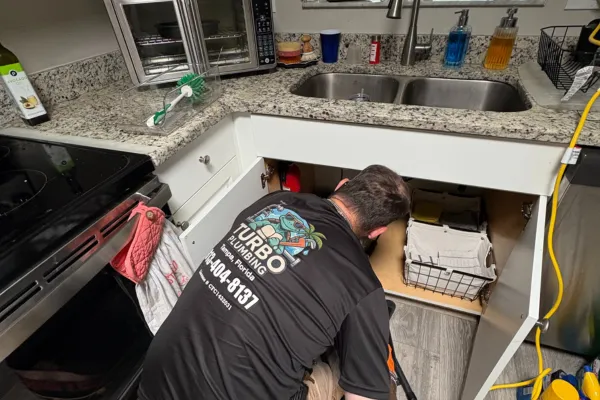 Turbo Plumbing Plumber in Tampa fixing something wearing a turbo plumbing shirt