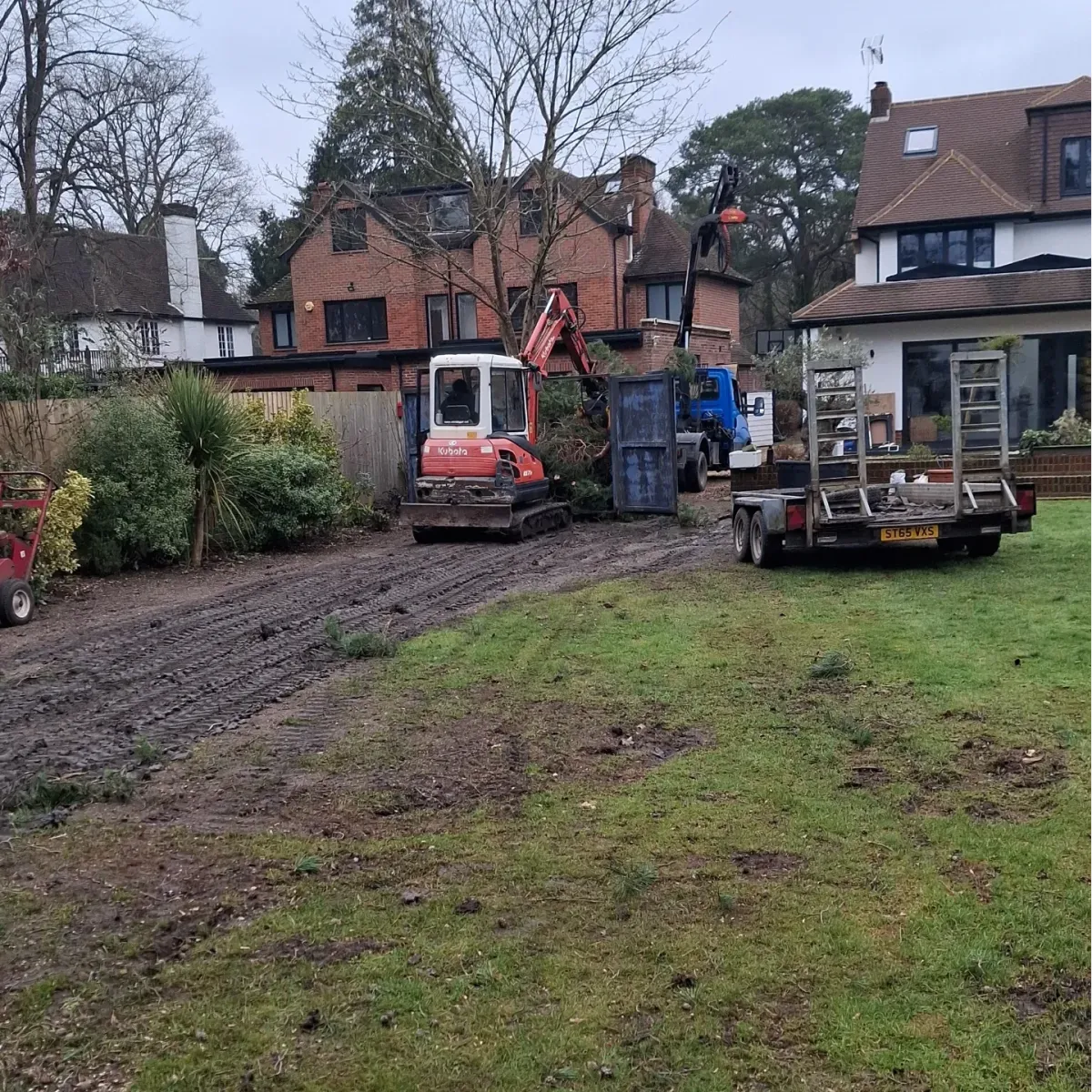 Mini excavator and trucks on site during garden clearance and tree work