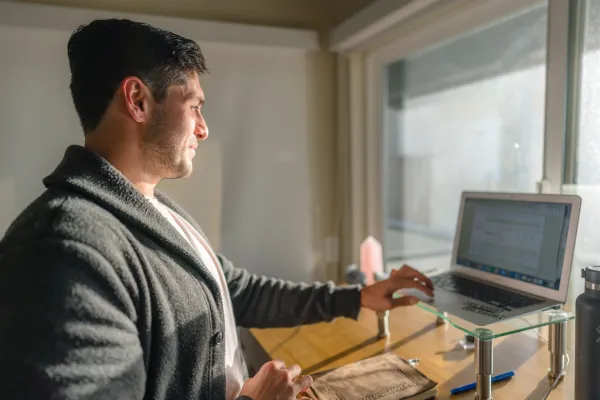 Joey Wilder working on SEO strategy at a standing desk in a bright home office, reviewing website analytics on a laptop