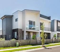 White modern townhouse with flat roof and neat garden under clear daylight.