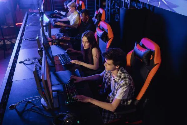 A group of people gaming in a room (gaming chairs and pc screens)