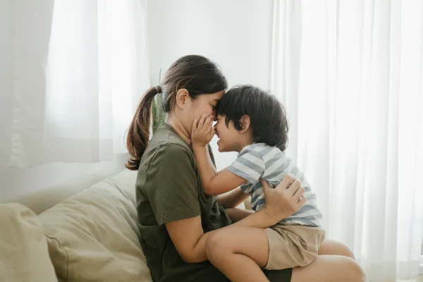 A mother and child looking at each other and cuddling on a sofa looking emotionally connected.