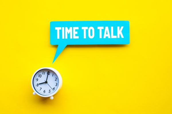Time to Talk in a speech bubble coming from a clock. Vibrant yellow background, and bright blue speech bubble.