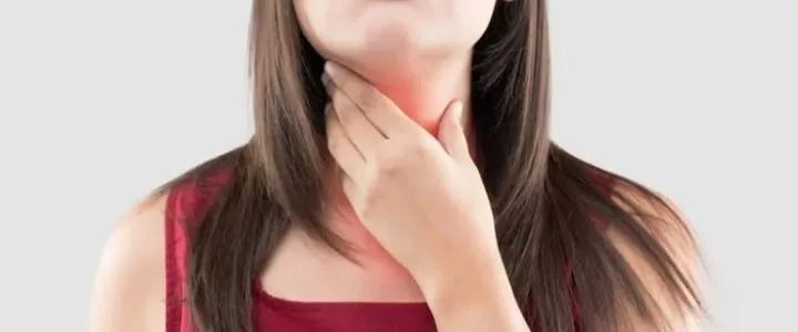 Femme se touchant la gorge, illustrant une enflure ou une gêne liée à un lymphome du manteau.