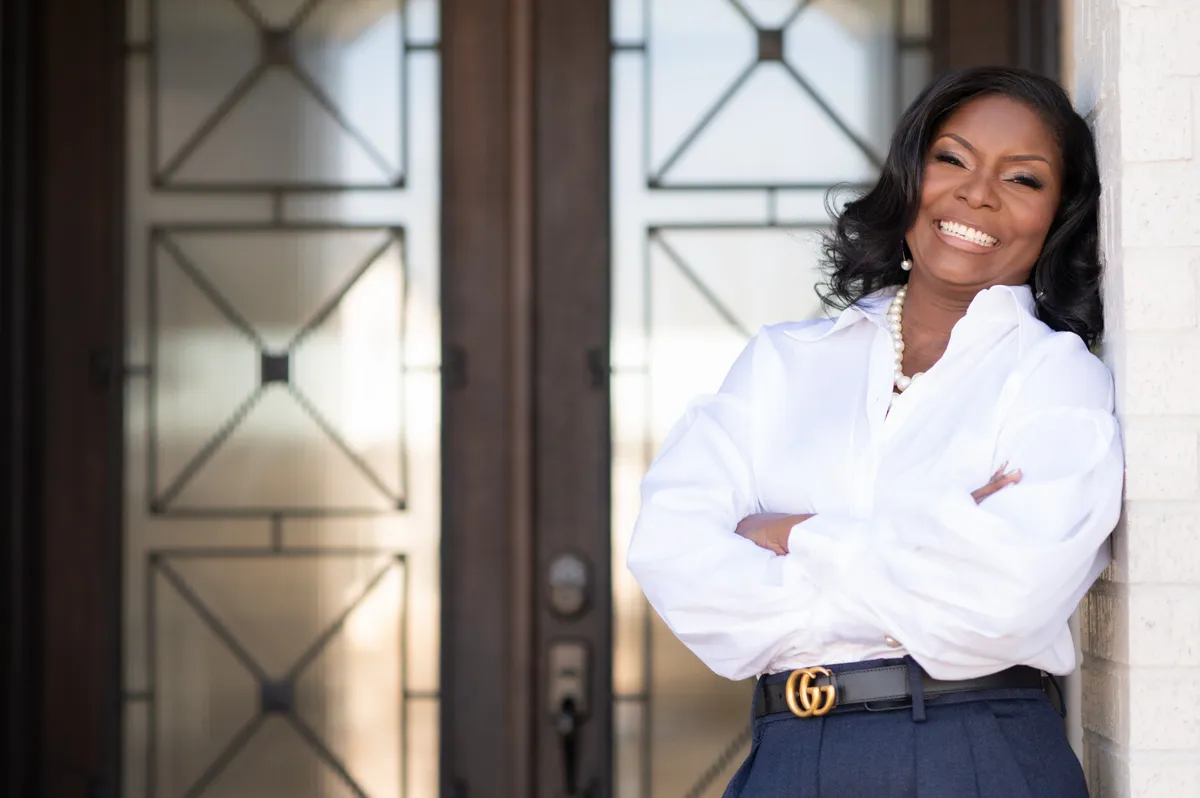 Coach Michelle smiling in a white blouse, standing with her arms crossed