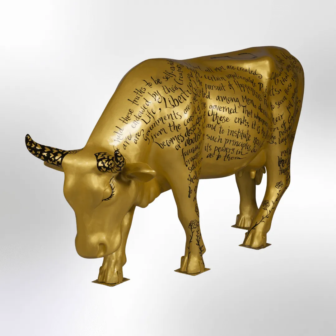 A shiny gold cow covered in the words of the Declaration of Independence in black decorative writing