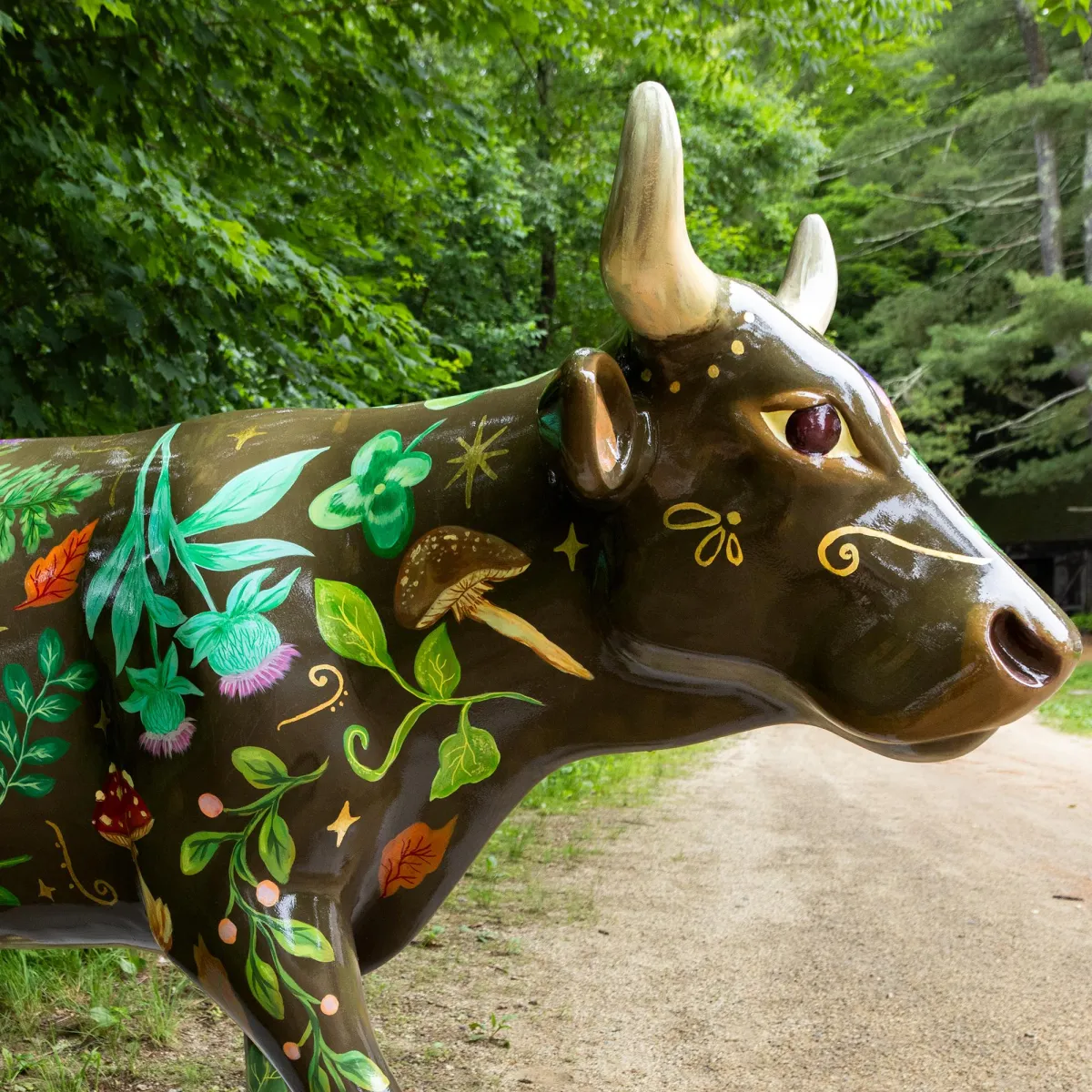 A cow sculpture painted with a moon, stars, mushrooms, and flowers
