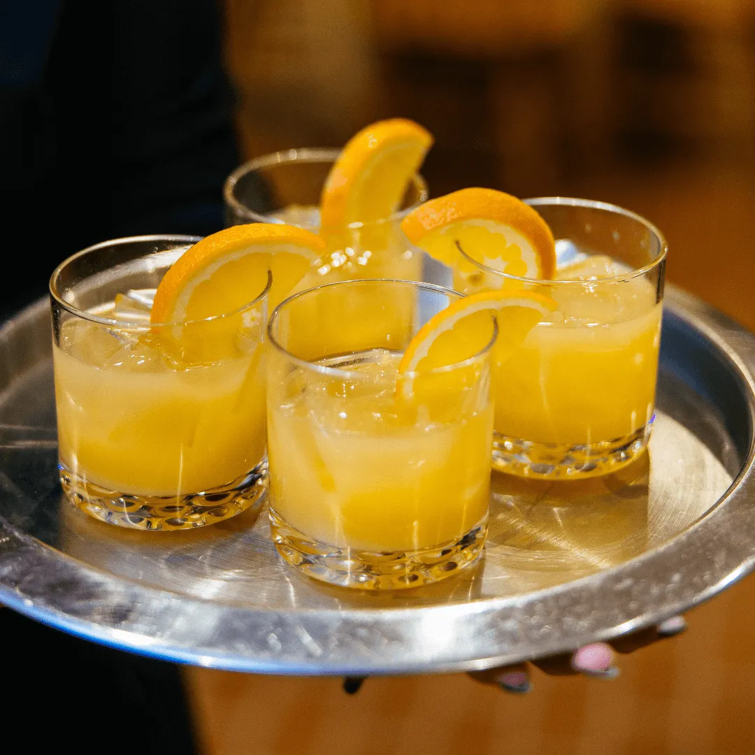 Four orange cocktails on a platter
