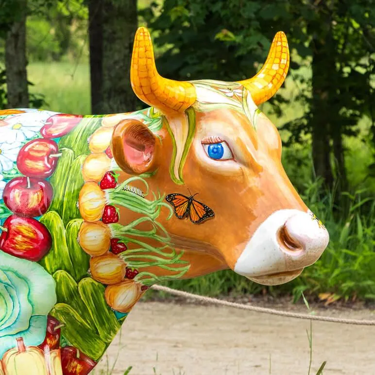 A cow sculpture painted with a variety of fruits, vegetables, and flowers