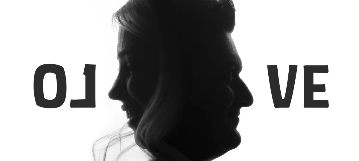 A black and white artistic silhouette of two faces in profile, merging into one central form, with partial letters "O L" on the left and "V E" on the right, forming the word "LOVE".