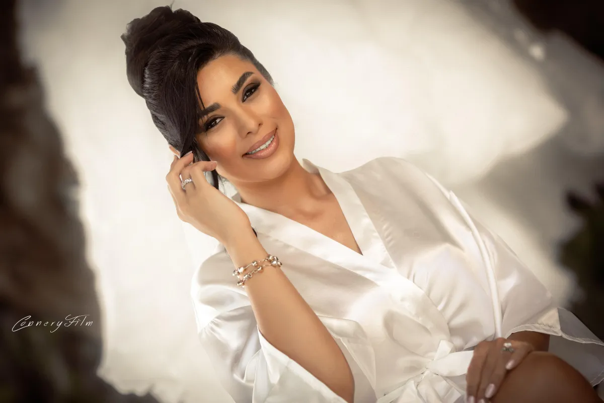 Bridal portrait of Niki smiling in a white silk robe, captured in soft natural light before her wedding.