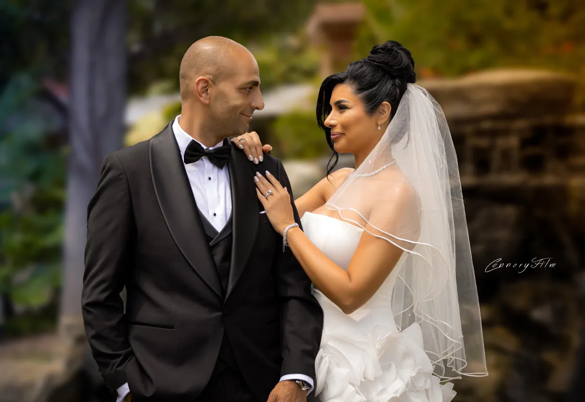 Bride Niki and groom Peyman smiling and looking at each other on their wedding day in elegant attire.