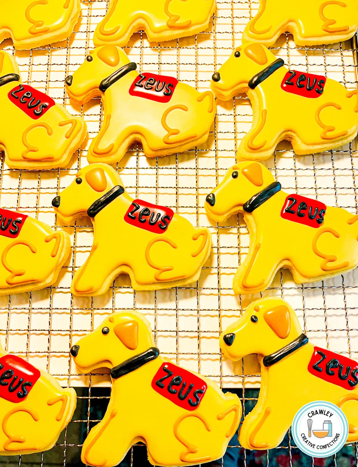 A beautifully crafted sugar cookie shaped like a sitting golden retriever, decorated as a seeing-eye dog named Zeus. The cookie features intricate hand-iced details, including Zeus’s golden fur, kind eyes, and a harness to signify his role as a guide dog. His name, “Zeus,” is written elegantly nearby, capturing his loyal and noble spirit.