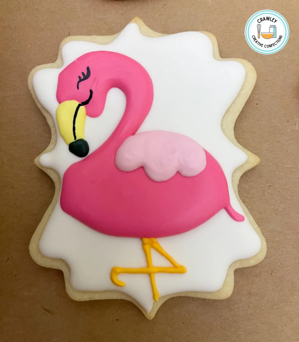 A playful sugar cookie decorated as a pink flamingo standing gracefully on one leg. The design features vibrant pink icing with detailed feather textures, a curved neck, and a black-tipped beak. The whimsical pose and intricate details bring this tropical theme to life.