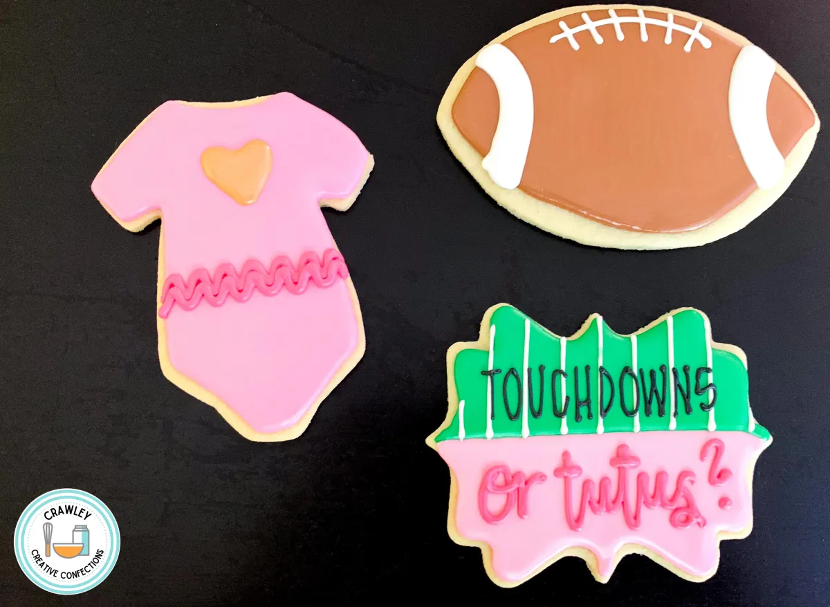 A playful set of sugar cookies for a “Touchdowns or Tutus” gender reveal shower. The designs feature hand-iced footballs and adorable tutu onesies in pink and blue. Each cookie is intricately detailed, perfectly blending sporty and sweet elements to celebrate the exciting reveal.