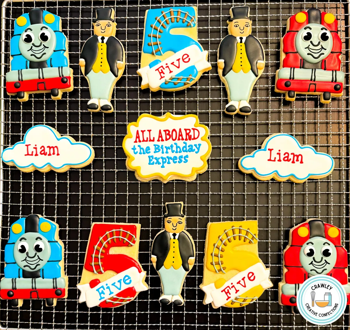 A playful set of sugar cookies for a 5th birthday party themed around Thomas the Tank Engine. The designs include hand-iced cookies shaped like Thomas, James, and Sir Topham Hatt, with vibrant colors and detailed accents. The cookies bring the beloved characters to life in a fun and festive way, perfect for a train-themed celebration.