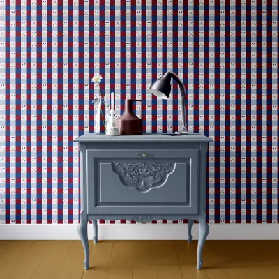 A dresser in front of a wall with a gingham wallpaper print.