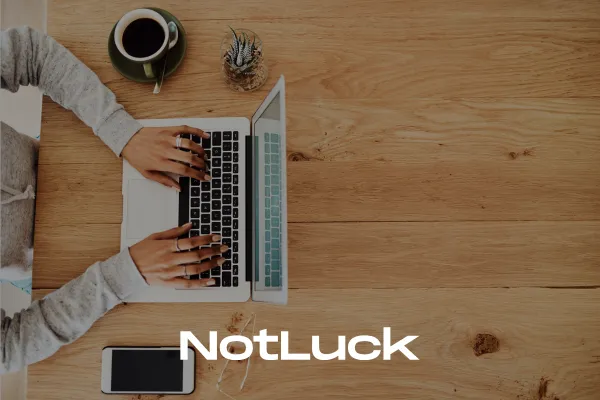 Overhead view of a person typing on a laptop at a wooden desk with coffee and a smartphone, symbolising small business owners writing blog content to improve SEO, increase brand visibility, and connect with their audience.
