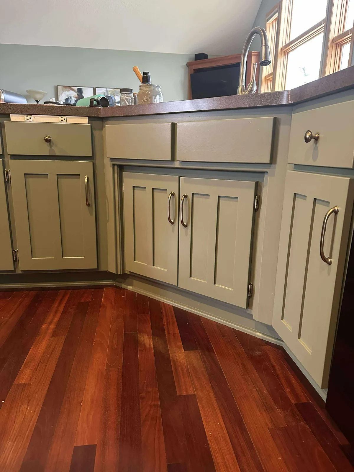 Finished olive green kitchen cabinets with clean paint lines and modern style
