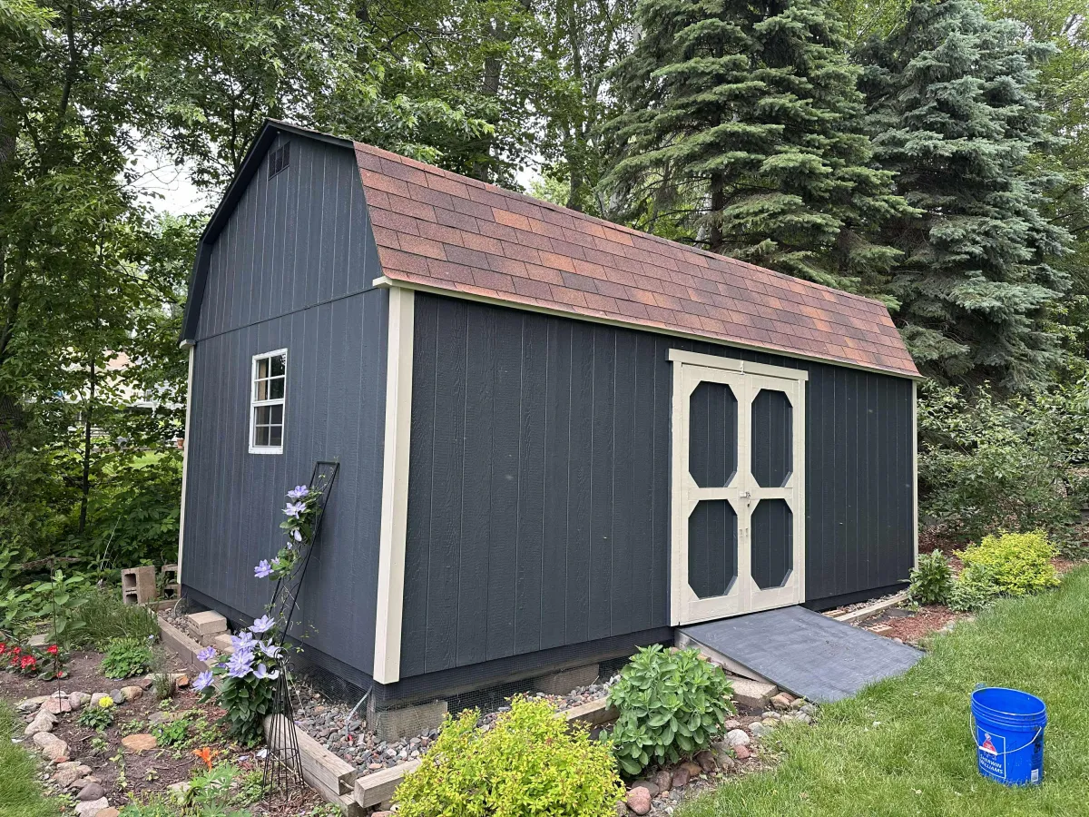 Dark blue painted shed with white trim in a backyard setting