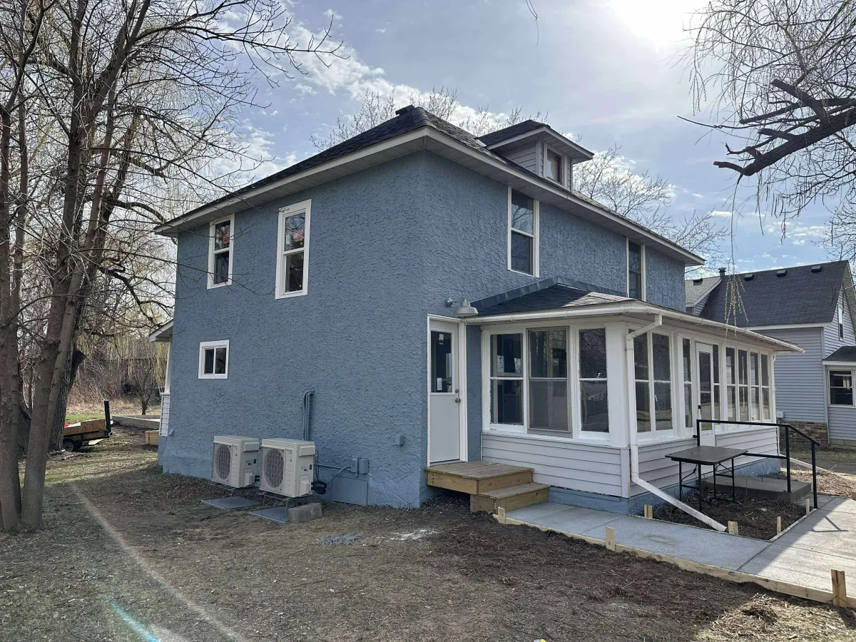 Freshly painted house exterior in blue-gray with white trim after full repaint