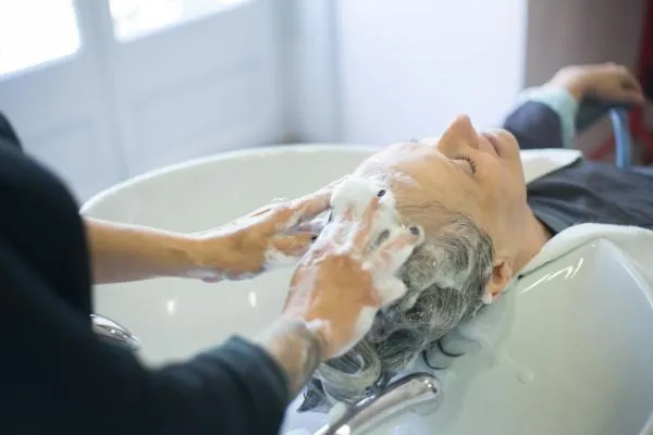 A senior woman gets her hair washed and cleaned at the salon.