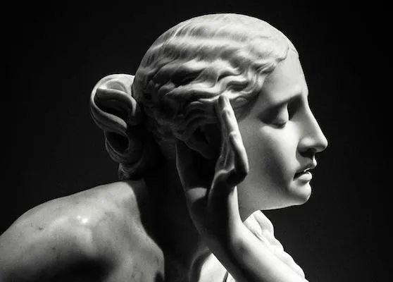 ancient statue of a woman with a hand next to her ear listening