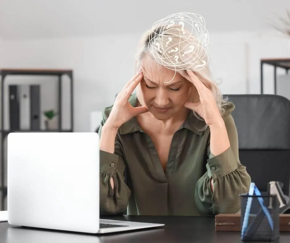 woman staring at computer with hands on either side of her head