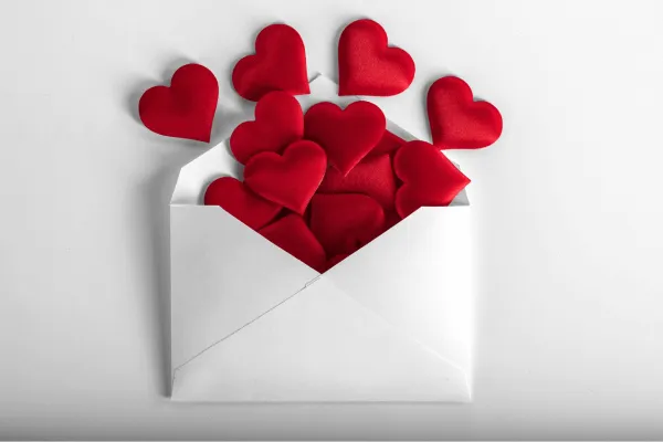 This image shows a white envelope overflowing with red hearts, symbolizing love, affection, and warm sentiments. It's a perfect visual representation for Valentine's Day, romantic messages, or themes of love and self-care. Use this image to complement content about relationships, self-love, or heartfelt gestures.