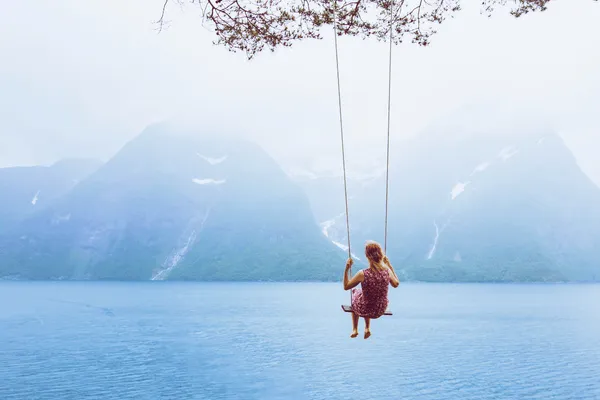 woman on a swing over water