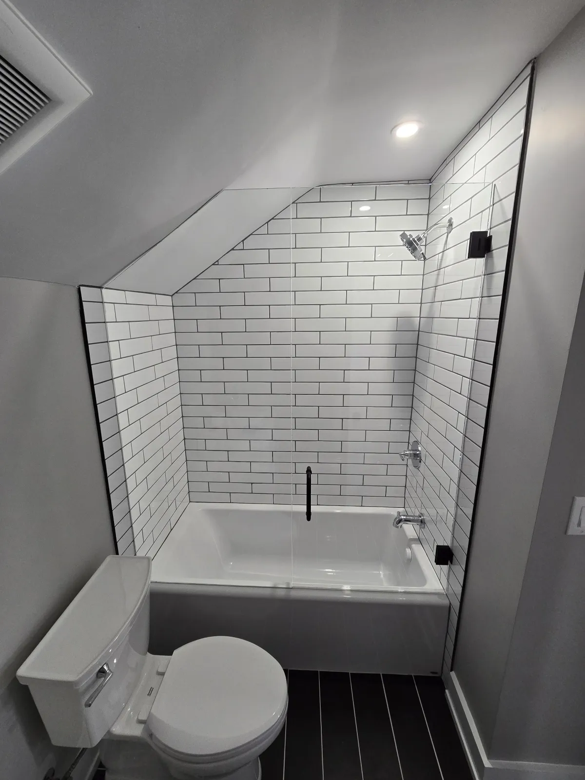 Frameless glass shower panel with white subway tile tub enclosure in Dayton OH bathroom