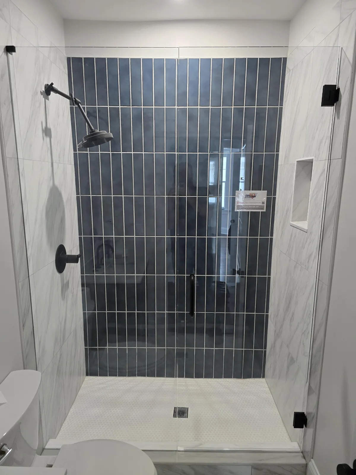 Frameless glass shower enclosure with vertical blue tiles and black hardware in Beavercreek OH