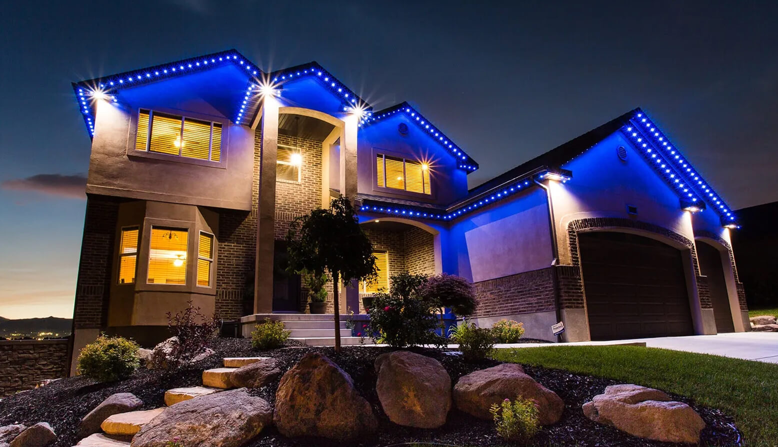 Custom blue LED roofline lighting installed on luxury home in Draper Utah with permanent outdoor lighting system by PowerHouse Roofing