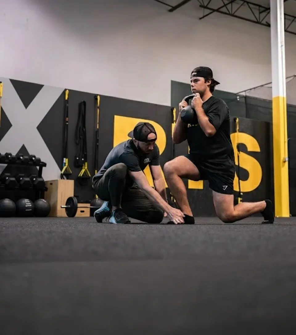 Athlete performing strength training exercise with physical therapist supervision during performance PT in Montclair facility