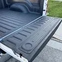 white truck with black sprayed in bedliner, close up on open tailgate and part of bed