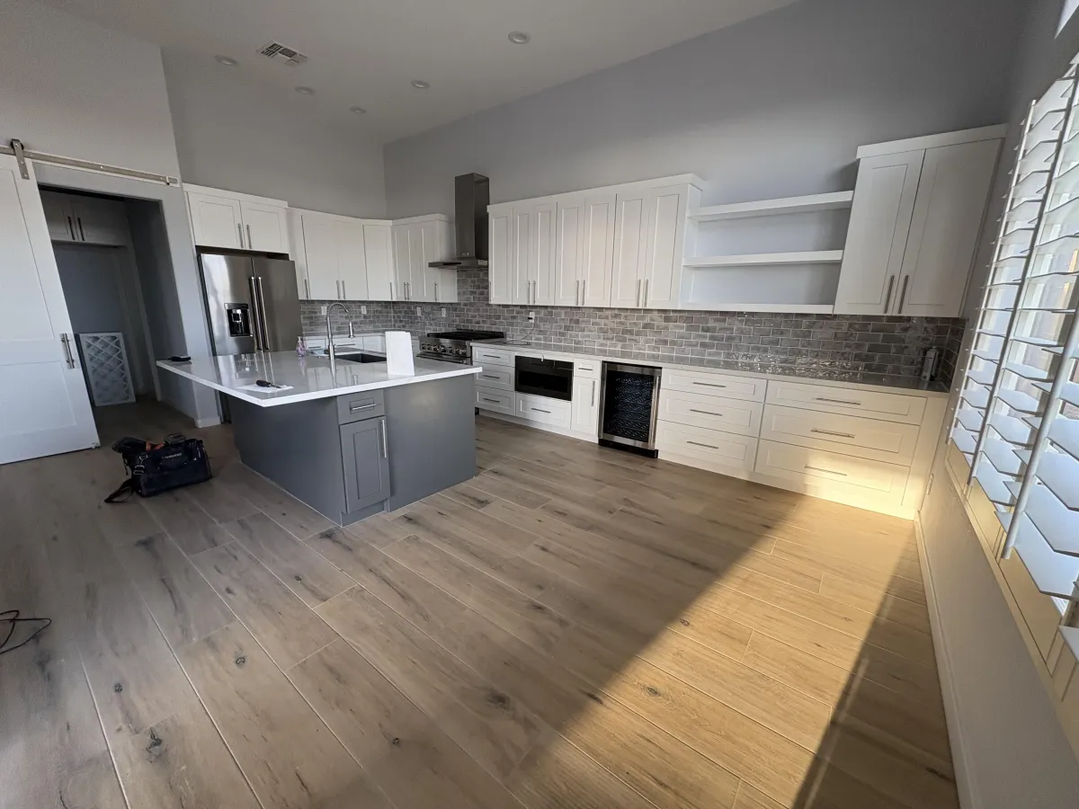 Modern Phoenix kitchen remodel featuring white shaker cabinets, a gray center island with quartz countertop, stainless steel appliances, subway tile backsplash, and wide plank wood flooring—showcasing bright, spacious, and contemporary design.