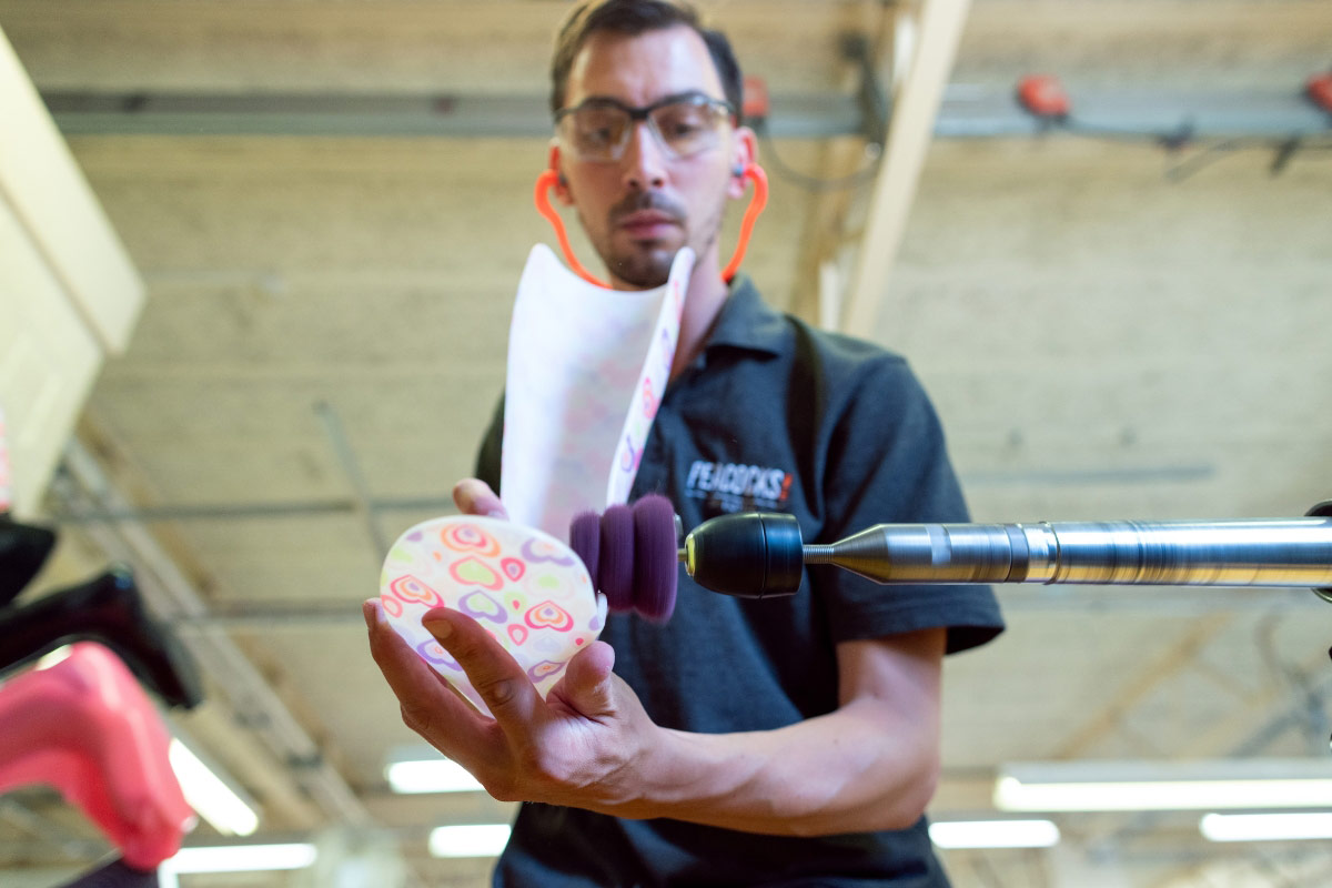 Orthotics technician polishing a custom brace component in a lab. Caption: We scan, design, and finish your device to match your anatomy and activity level.