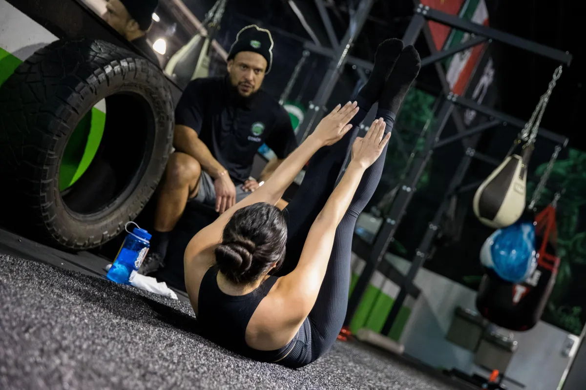 A client doing leg raises being personally trained by a coach.