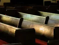 Empty church pews with a single light on — metaphor for absent care