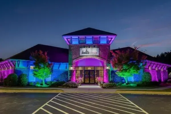 Exterior of a dance studio called Danceworks, lit up with colorful landscape lighting