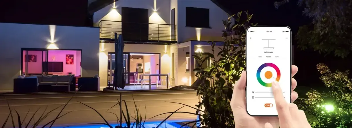 Someone displays a smartphone that controls vibrant, color-changing lights, highlighting the convenience of smart home tech.